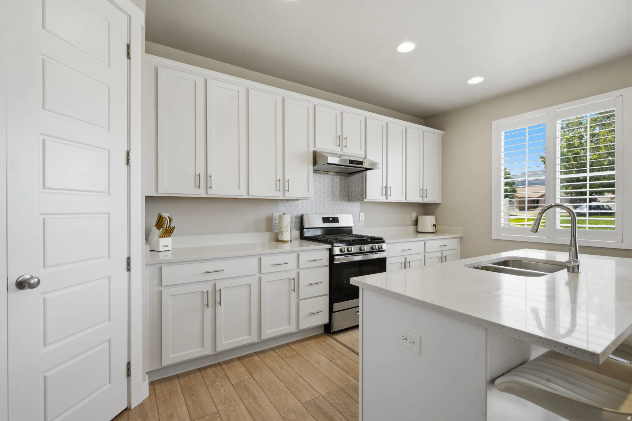 Kitchen featuring white shaker-style cabinetry, a stainless steel gas range, and a coordinating range hood