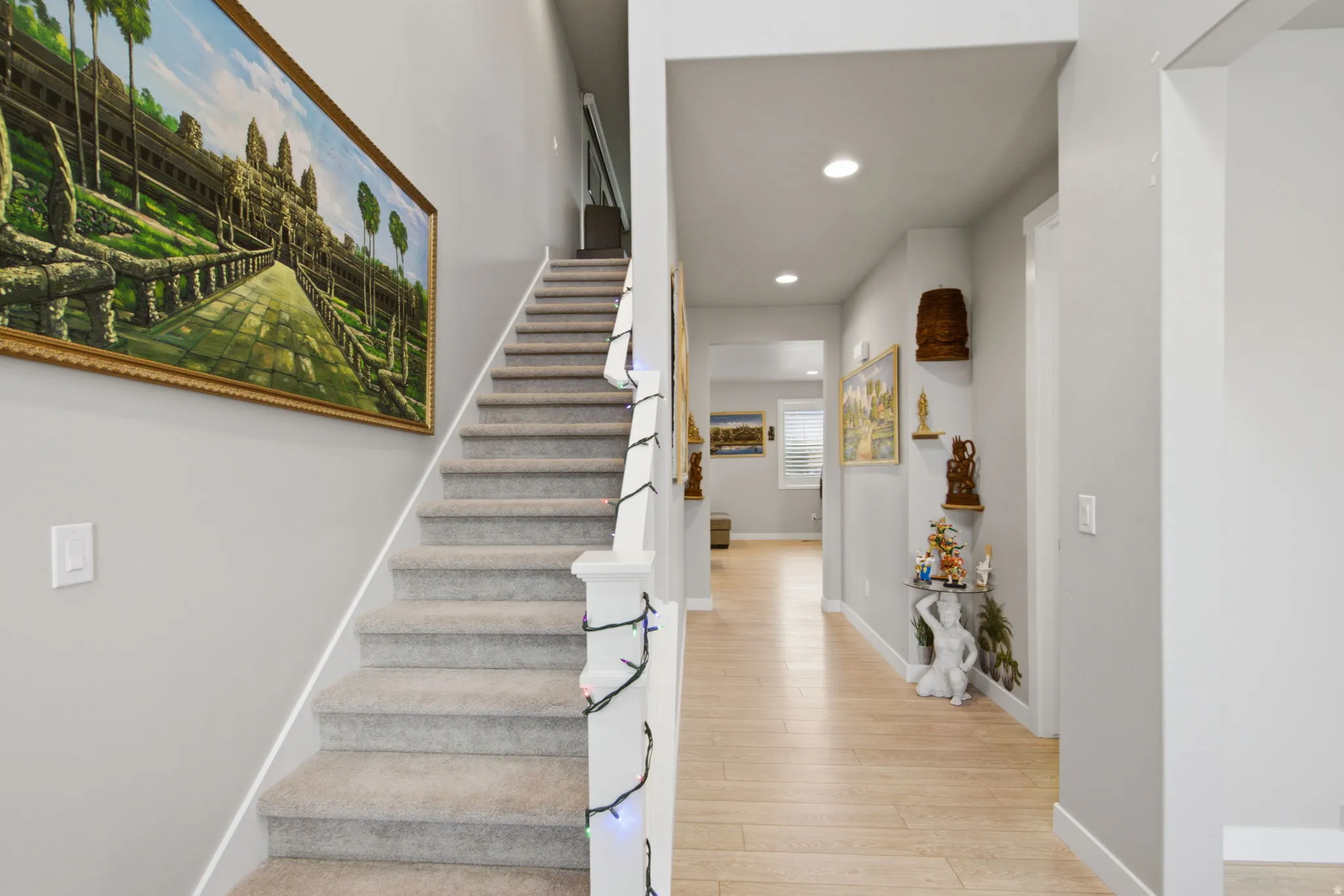 Carpeted staircase with white balusters, recessed lighting, and light wood-finish flooring in the hallway