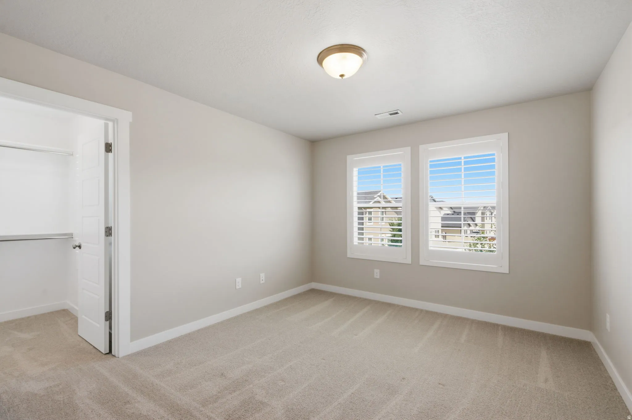 Spacious room featuring neutral carpeting, light-toned wall paint, and white trim