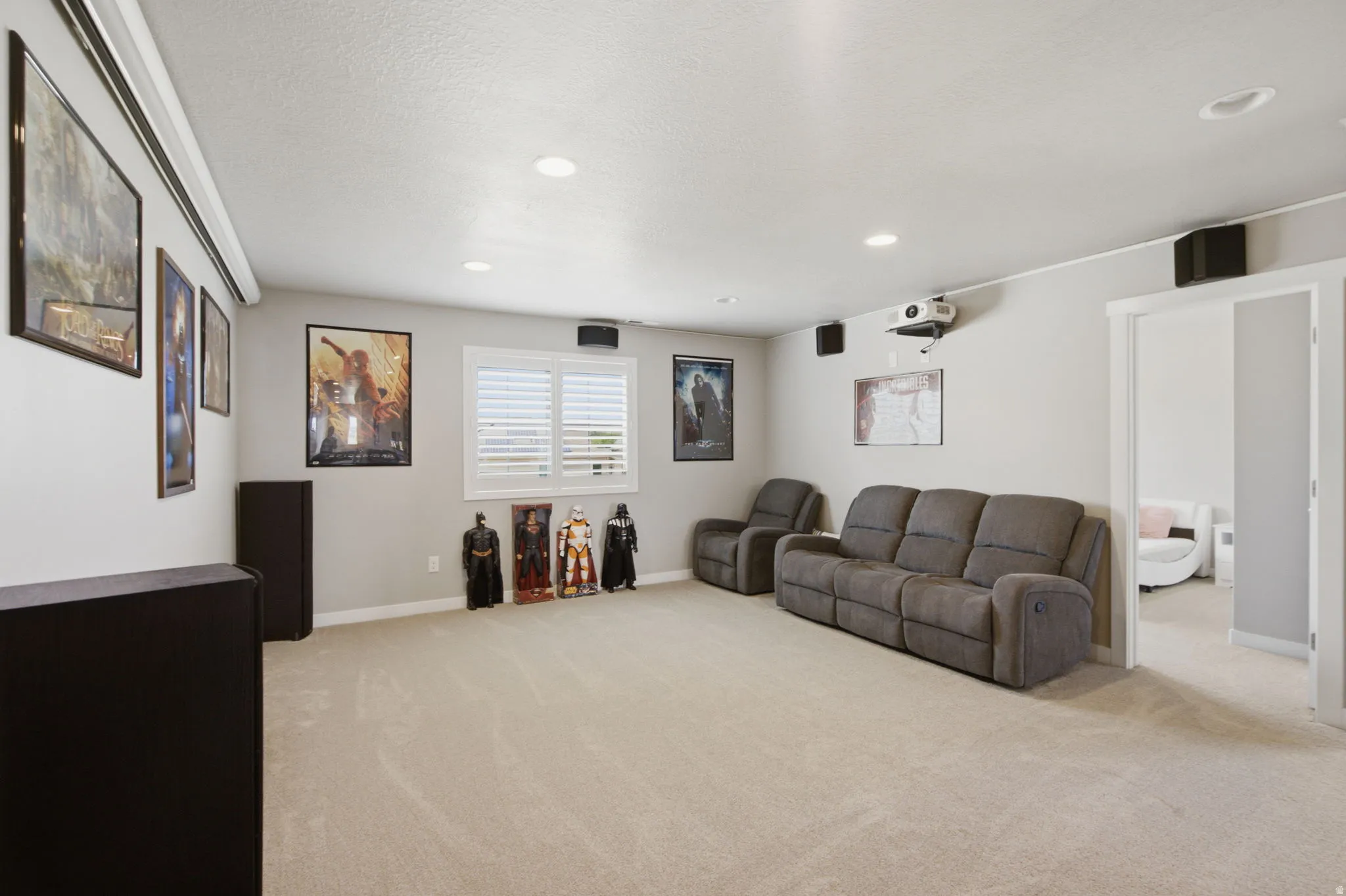 Dedicated entertainment room featuring recessed ceiling lighting, a mounted projector, and a wall-mounted projection screen
