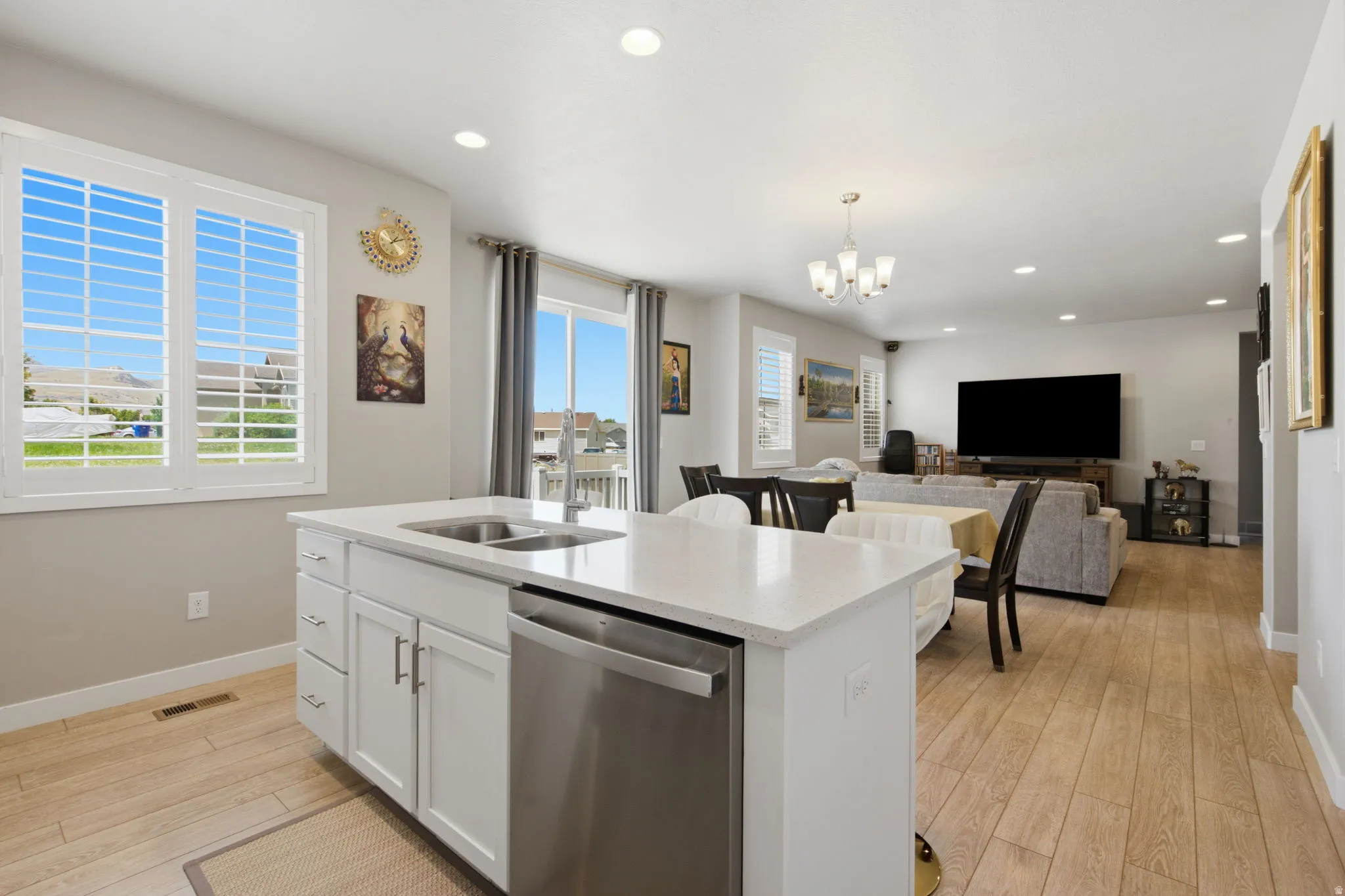 Kitchen island featuring a stainless steel sink, integrated dishwasher, and white cabinetry
