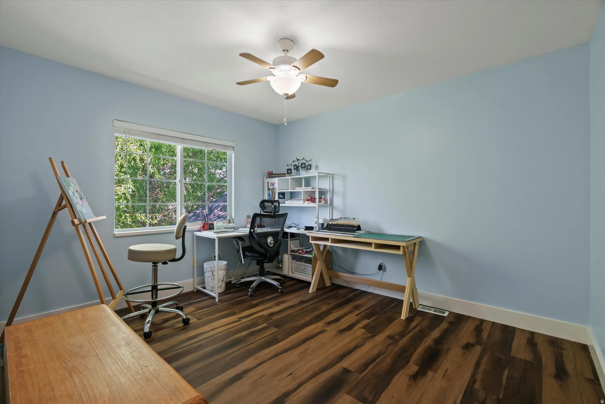 Room featuring wood-finish flooring, a window offering natural light, and a ceiling fan with integrated lighting