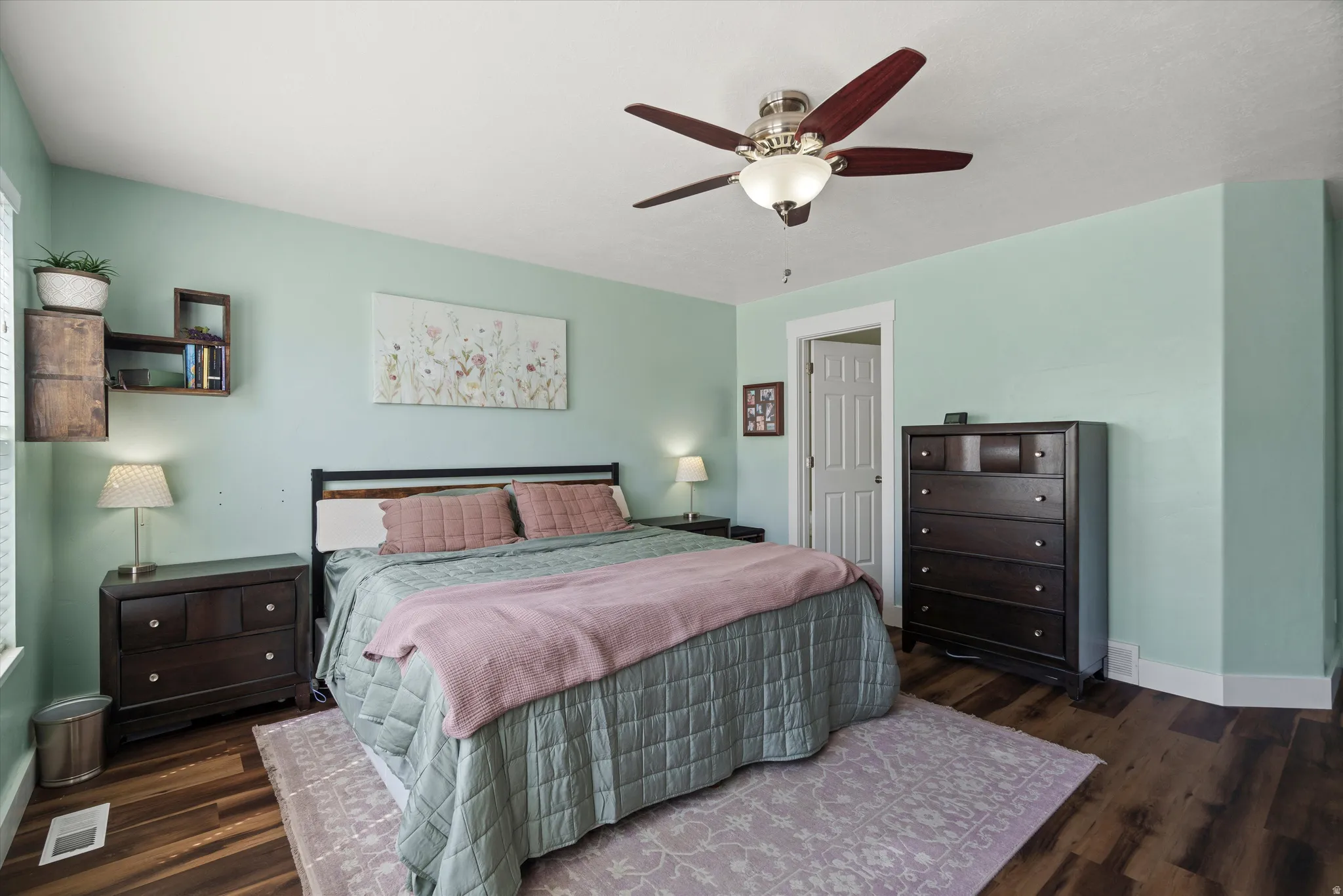 Spacious room featuring wood-finish flooring, a ceiling fan with integrated lighting, and light-colored walls
