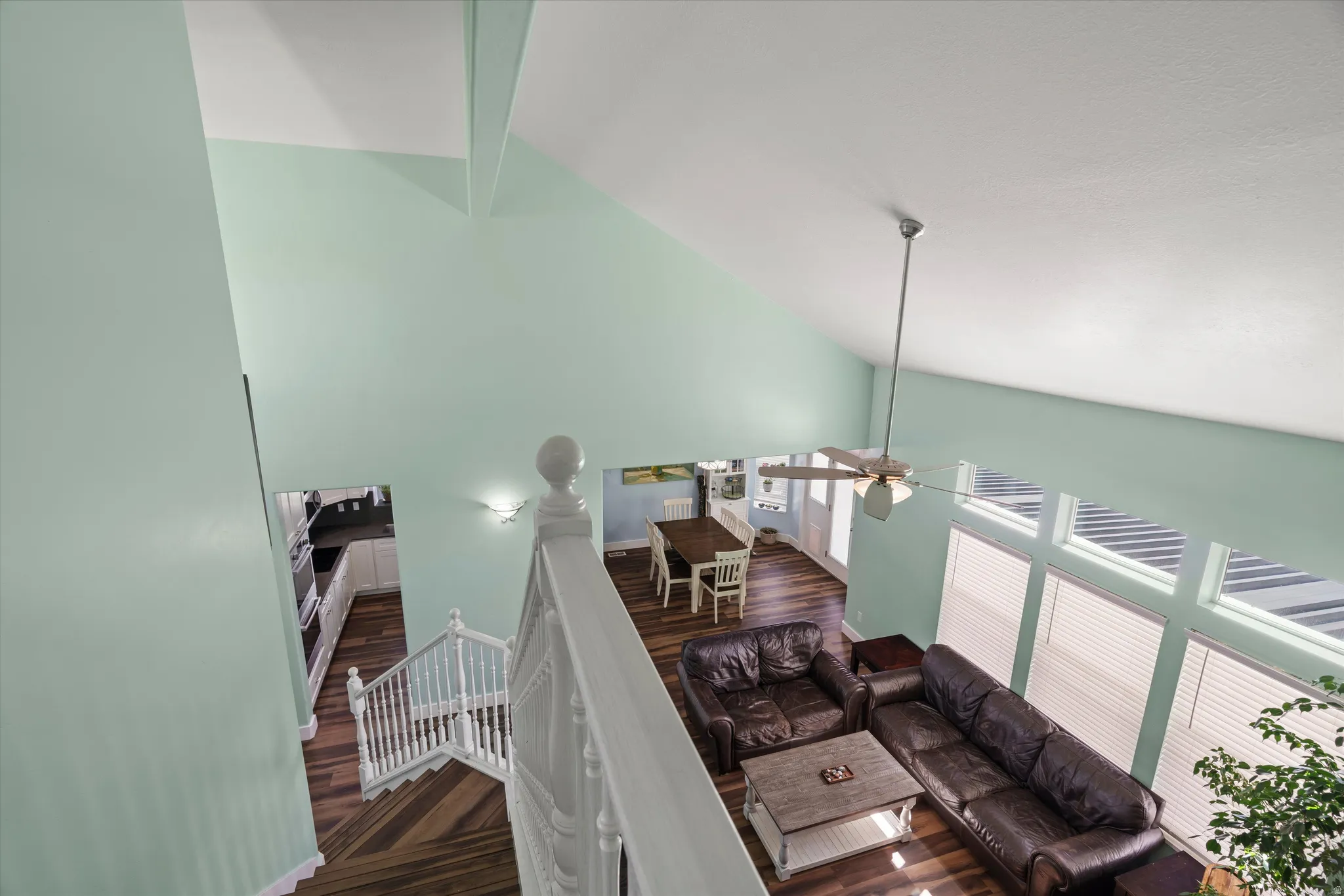Open-concept living space with vaulted ceilings, a ceiling fan, and large windows with blinds