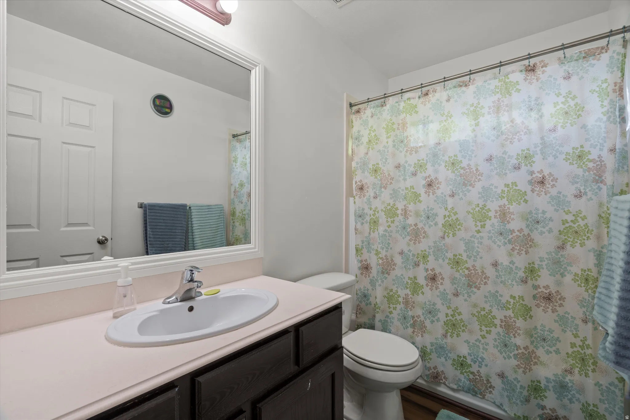 Bathroom vanity featuring an integrated oval sink, chrome faucet, and a large framed mirror with overhead lighting