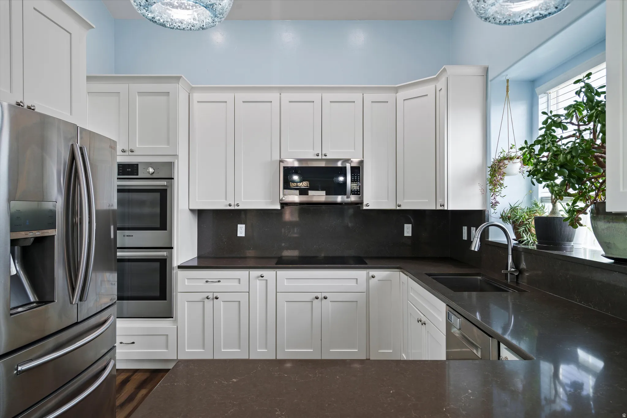 Kitchen featuring white shaker cabinetry, dark countertops, and a built-in double oven