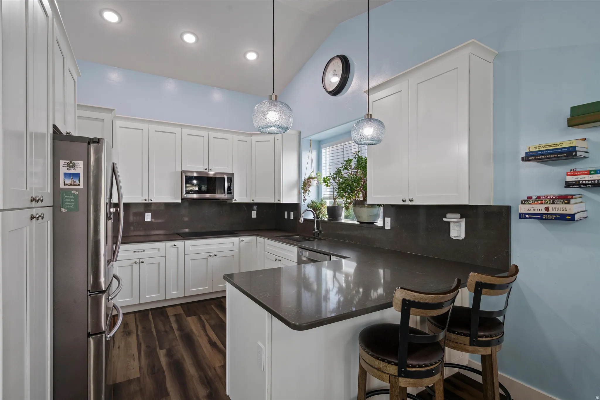 Kitchen featuring white cabinetry, dark countertops, stainless steel appliances, wood-finish flooring, and recessed lighting