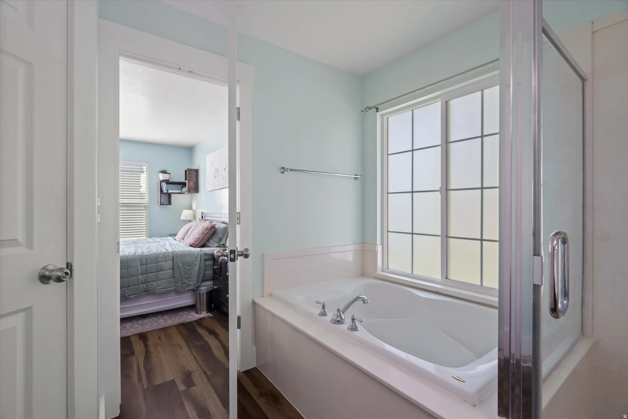 Soaking tub with chrome fixtures, framed by a window with grid patterns