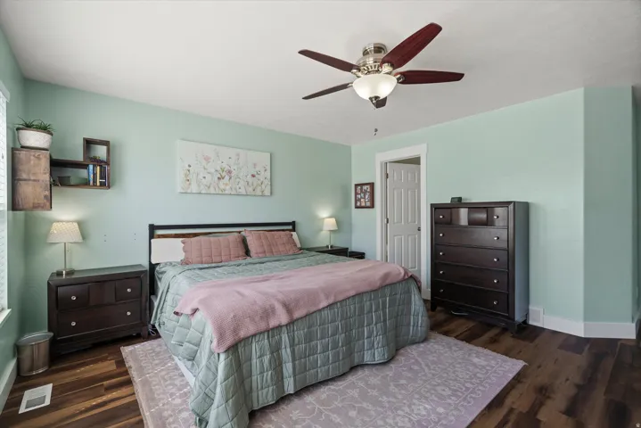 Spacious room featuring wood-finish flooring, a ceiling fan with integrated lighting, and light-colored walls