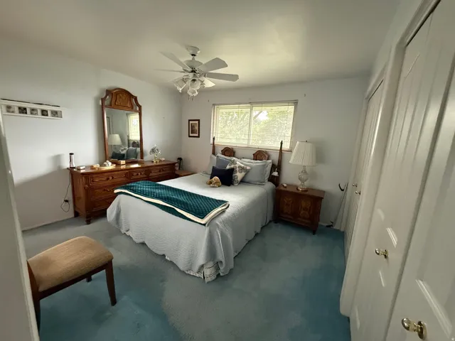 Spacious room featuring light blue carpeting, a ceiling fan, and a window with blinds