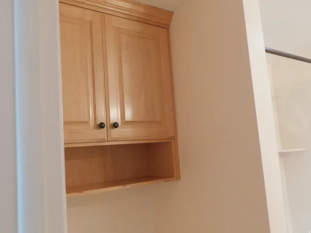 Light wood-finish cabinetry with crown molding and black hardware