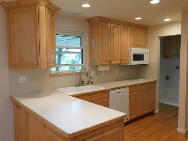 Kitchen featuring light wood cabinetry, recessed lighting, double basin sink with gooseneck faucet, light-toned countertops, and wood-finish flooring