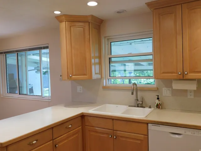 Kitchen featuring light wood cabinetry with brushed nickel hardware, white countertops, and a double basin sink with a gooseneck faucet