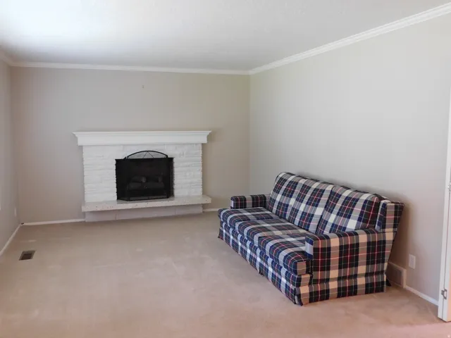 Living area featuring a painted brick fireplace with a white mantel and a stone hearth