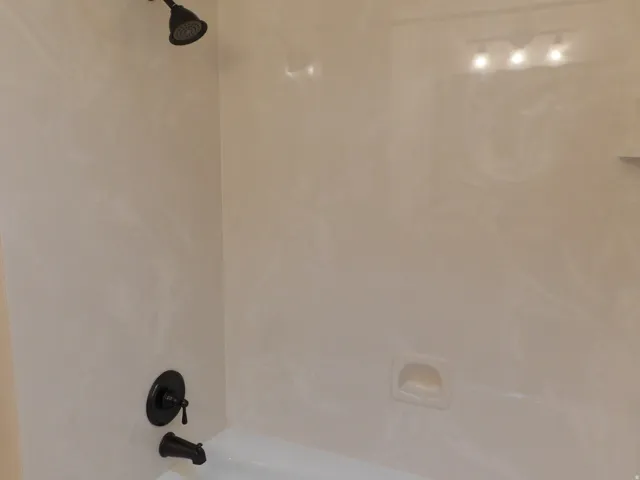 Tub and shower combination featuring oil-rubbed bronze fixtures and a built-in soap dish