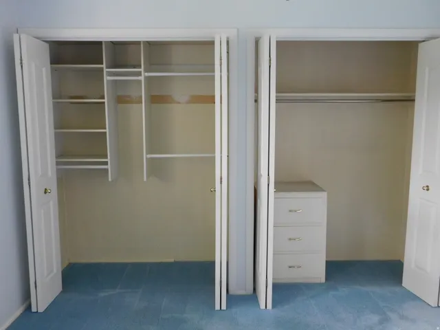 Dual closet spaces featuring bi-fold doors, white shelving, and hanging rods