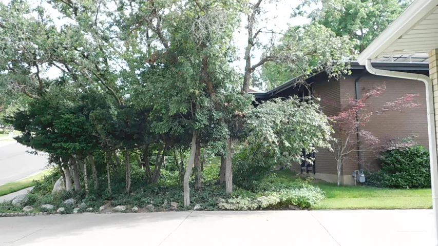 Brick exterior featuring a dark roofline, white gutters, and mature trees