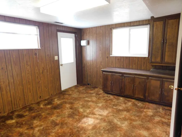 Interior room featuring wood-panel walls, patterned carpet, and multiple windows