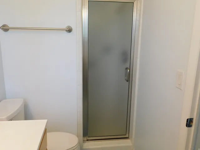 Shower enclosure with frosted glass door and brushed nickel handle