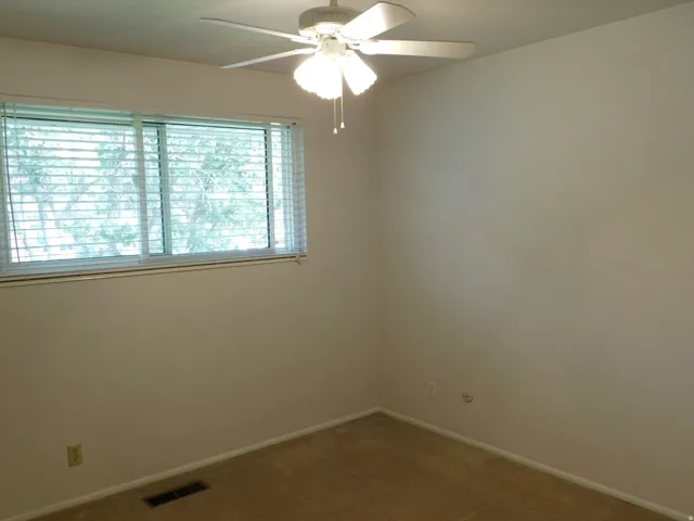 Neutral wall tones, plush carpeting, and a window with horizontal blinds