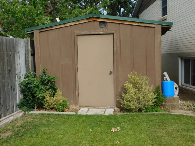 Freestanding storage shed with a brown wood-paneled exterior and a green roof