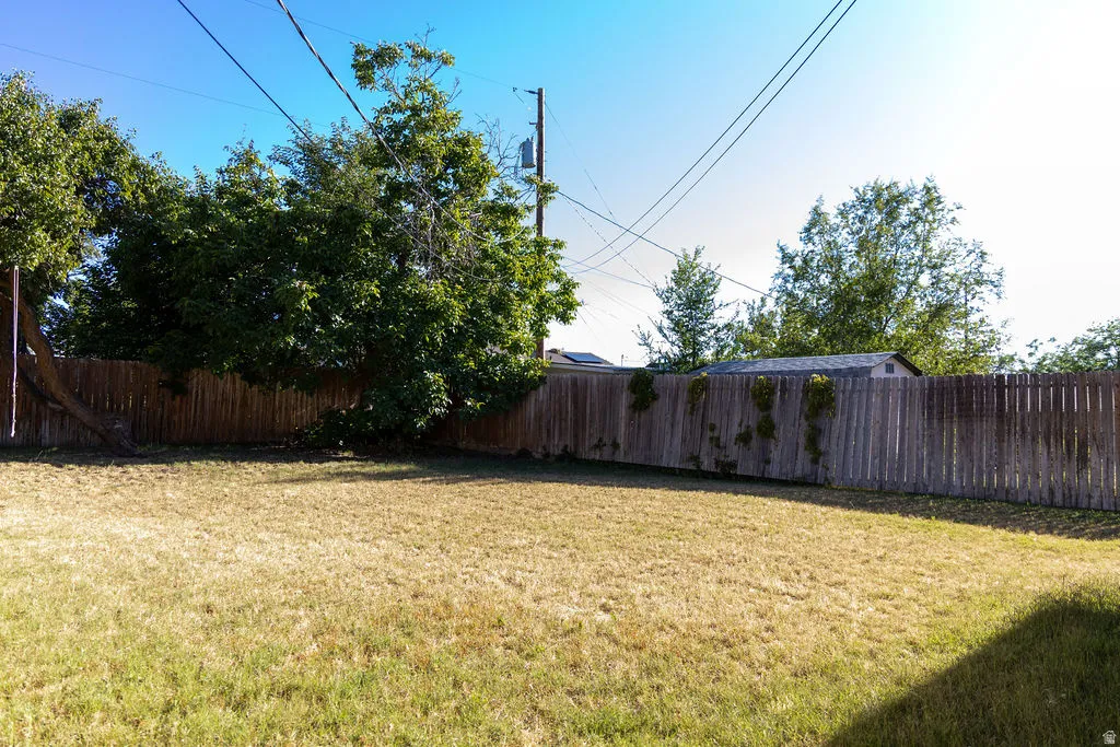 Expansive backyard featuring a wood privacy fence, mature trees, and a separate storage shed