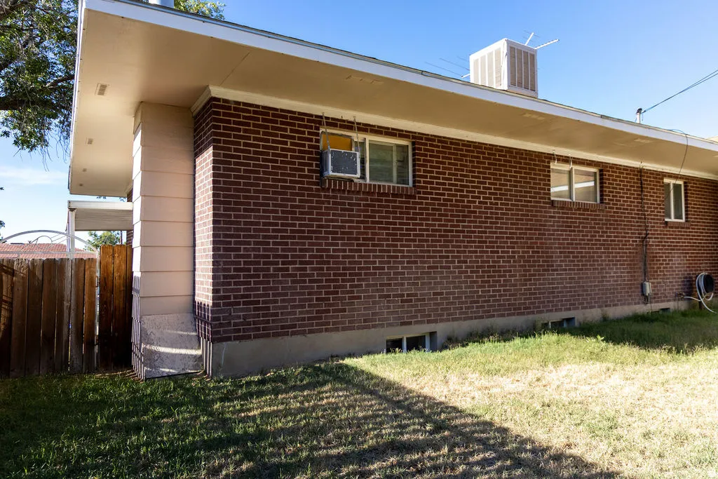 Brick exterior featuring multiple windows and a perimeter fence