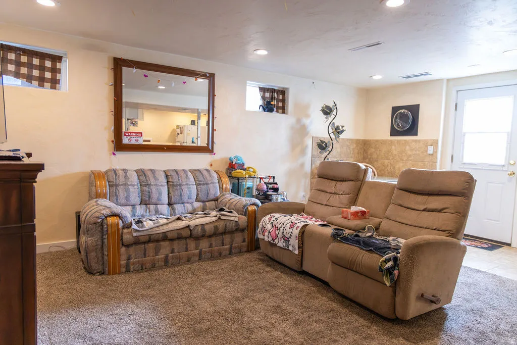 Carpeted room featuring recessed lighting, a window with horizontal blinds, and a paneled door with a window insert