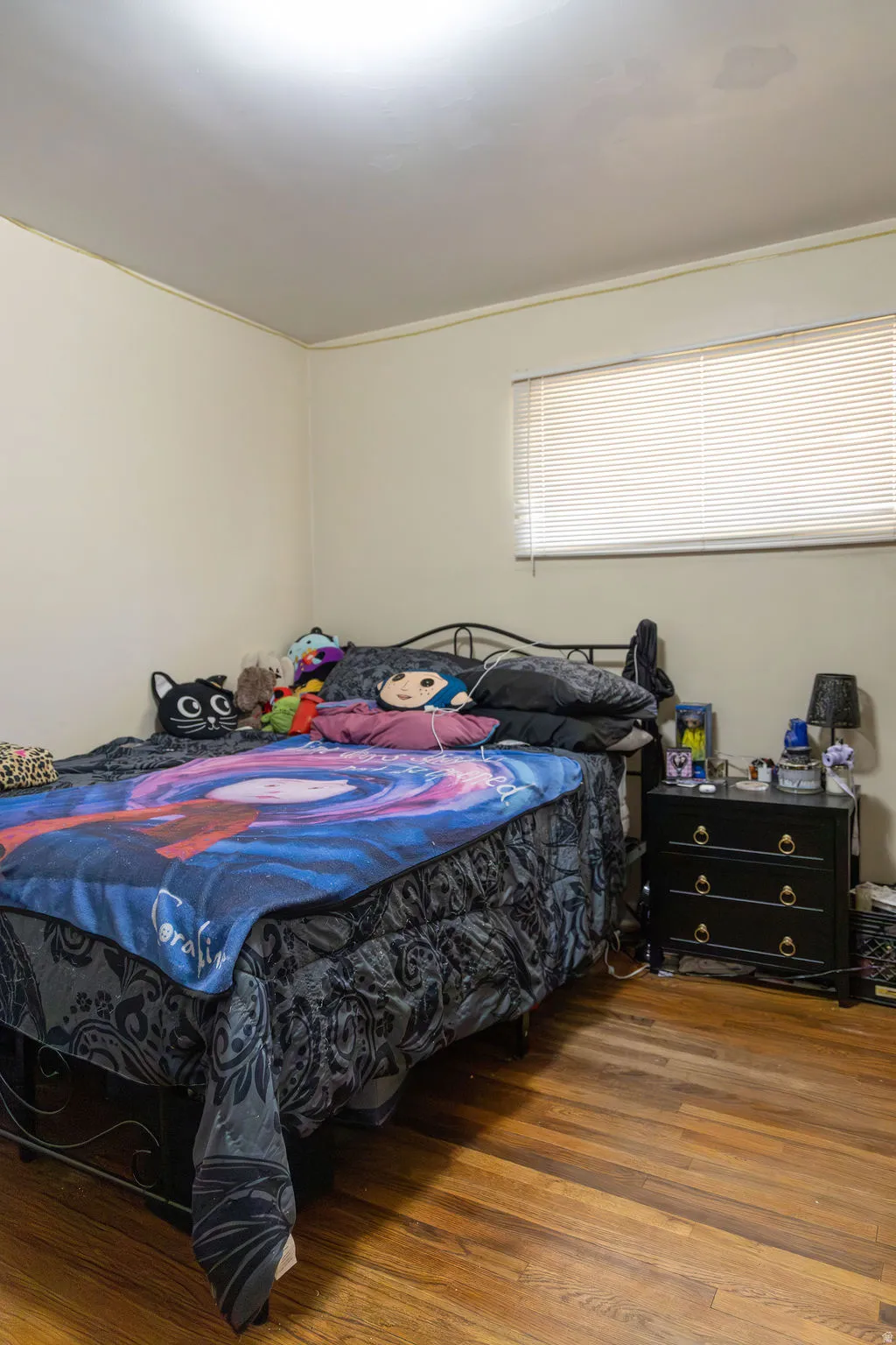 Room featuring light neutral wall paint, wood-finish flooring, and a single window with horizontal blinds