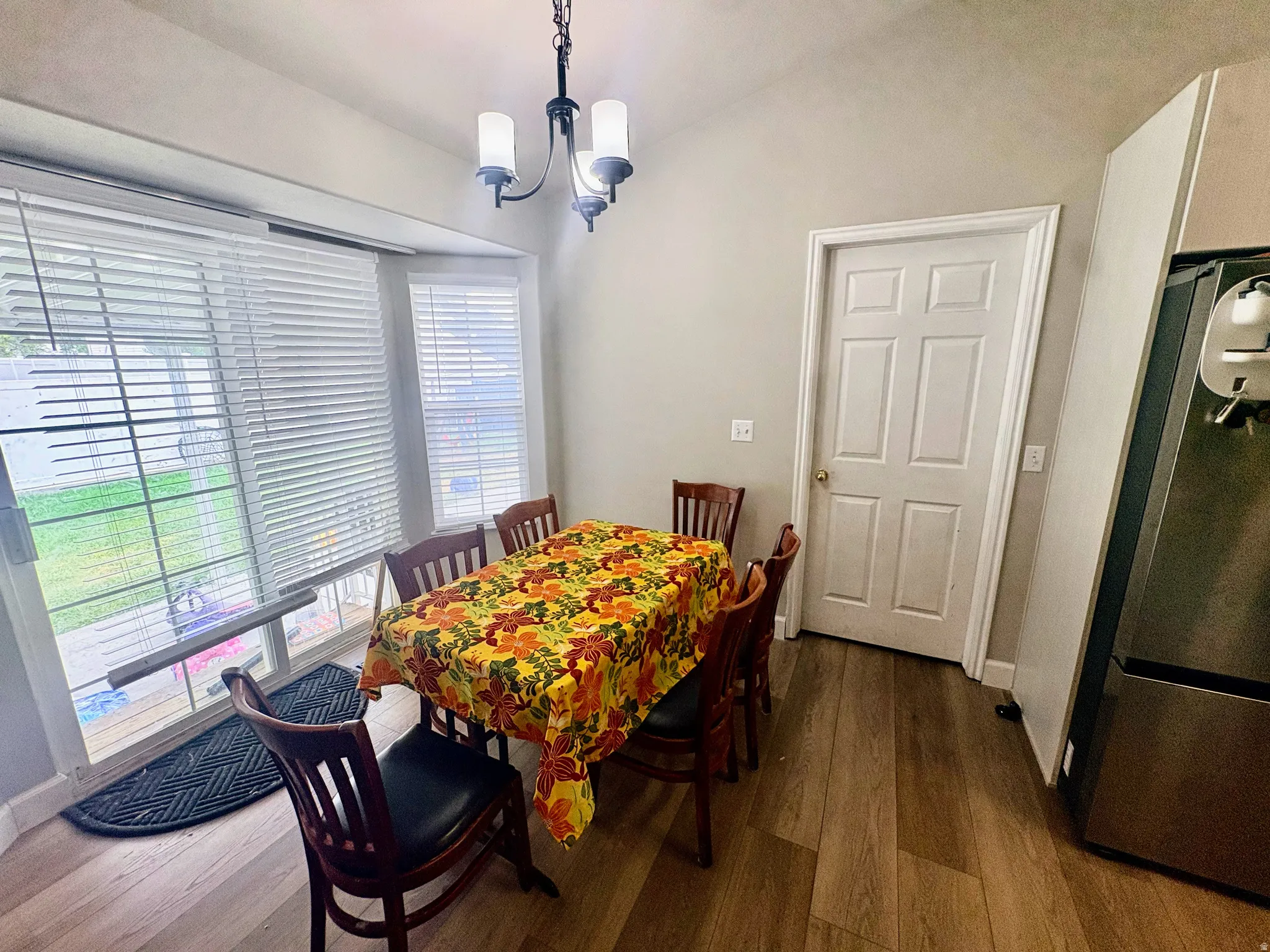 Dining area featuring wood-finish flooring, a contemporary chandelier, a sliding glass door, and a bay window