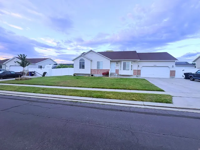 Single-story residence featuring light-colored siding, brick accents, an attached two-car garage, an arched window detail, and a white privacy fence
