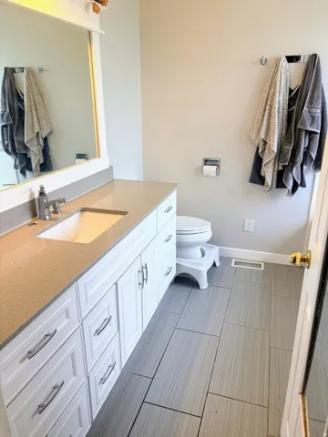 Master bathroom featuring a single vanity with white cabinetry, a light-toned countertop, and an undermount sink
