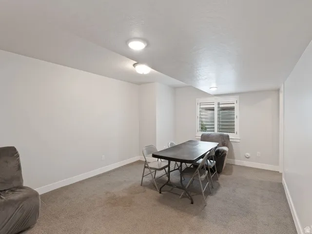 Carpeted room featuring a white baseboard, a window with horizontal blinds, and recessed lighting
