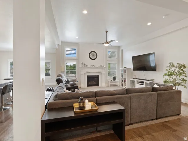 Spacious living area featuring a central fireplace with white mantel, shiplap accent wall, recessed lighting, and a ceiling fan