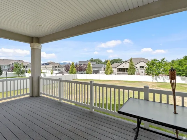 Covered patio featuring composite decking, white railing, and a slatted ceiling