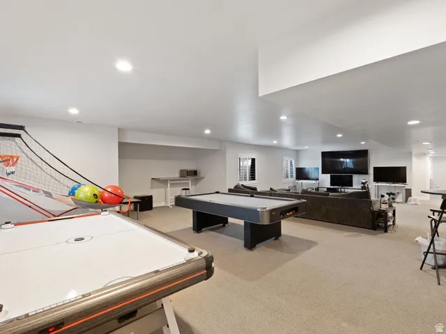 Expansive recreation room featuring recessed lighting, light-toned carpeting, and a visible window with plantation shutters