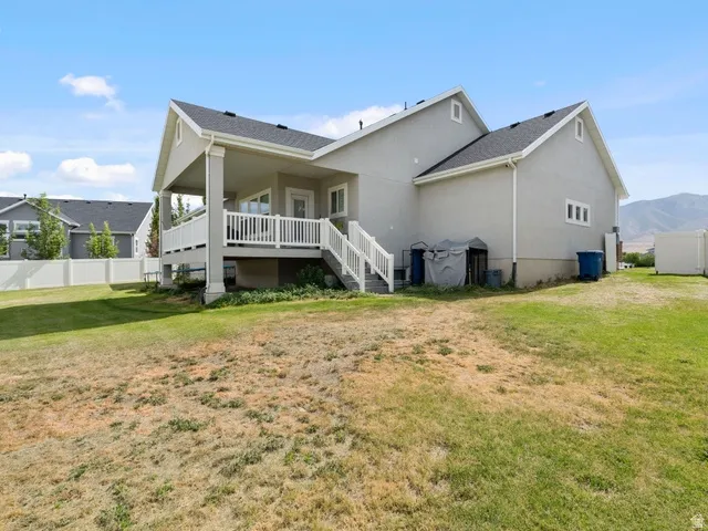 Expansive backyard featuring a partial vinyl privacy fence, a stucco exterior, and a covered patio with white railings