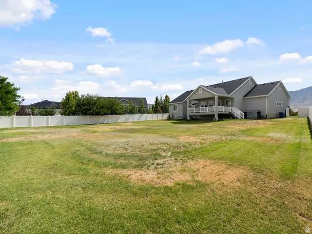 Expansive backyard featuring a large green lawn and a full vinyl privacy fence