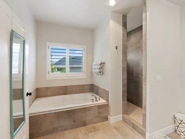 Soaking tub with a tiled surround, adjacent to a walk-in shower with large format tile walls and a hexagonal tile floor