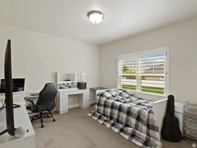 Spacious room featuring neutral carpeting, a large window with white plantation shutters, and a flush-mount ceiling light fixture