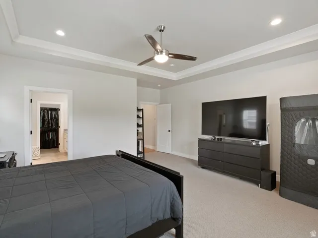 Recessed lighting illuminating a tray ceiling with crown molding, featuring a ceiling fan with integrated lighting