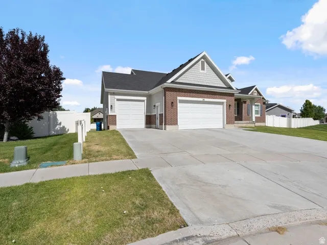 Brick and siding exterior featuring a three-car garage, pitched roofline, gabled accents, and a concrete driveway