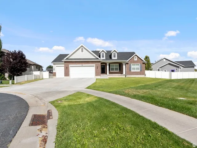 Brick and siding exterior featuring a three-car garage and a paved driveway