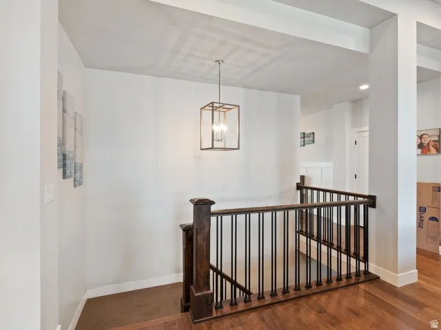 Staircase featuring dark wood newel posts, dark wood handrail, and black metal spindles