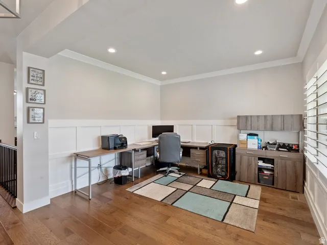 Office space featuring wood-finish flooring, wainscoting, recessed lighting, and window with plantation shutters