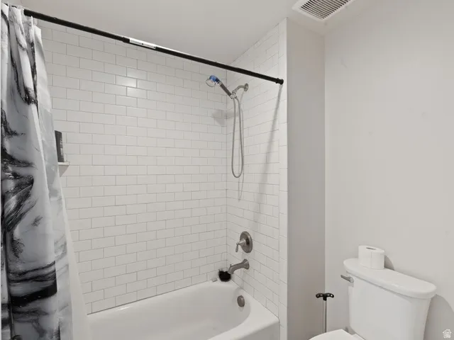 Bathtub with subway tile surround, brushed nickel fixtures, and a wall-mounted showerhead