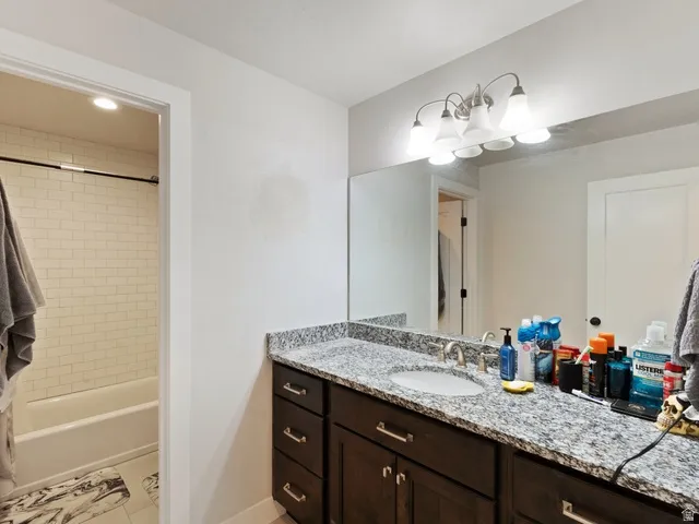 Granite-topped vanity with an undermount sink and dark wood-finish cabinetry