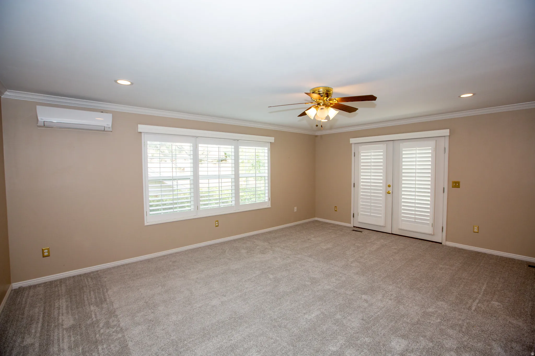 Spacious primary bedroom featuring neutral carpeting, a ceiling fan with integrated lighting, and recessed ceiling lights