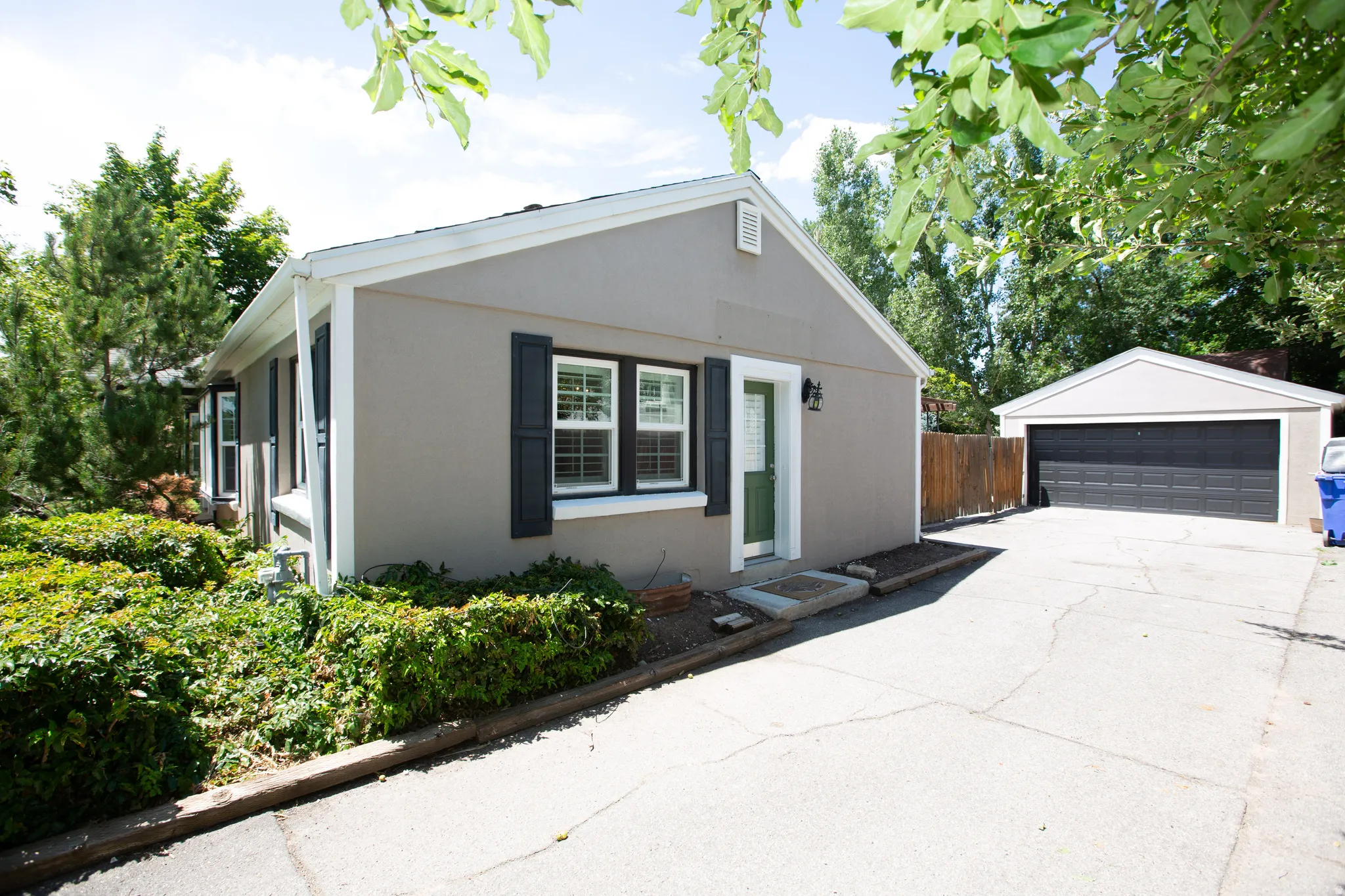 Single-story residence featuring a neutral-toned exterior, dark window shutters, and a contrasting green entry door