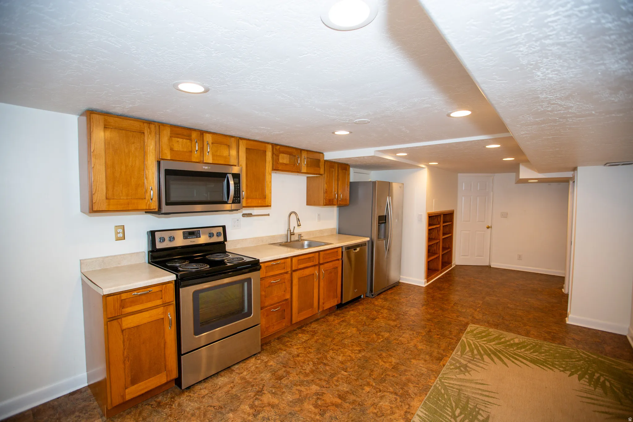 Kitchen featuring stainless steel appliances, wood cabinetry, light countertops, and recessed lighting